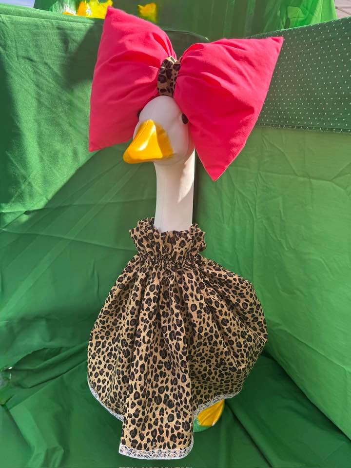 Lawn goose in a leopard-print dress with a hot pink bow against green draped fabric